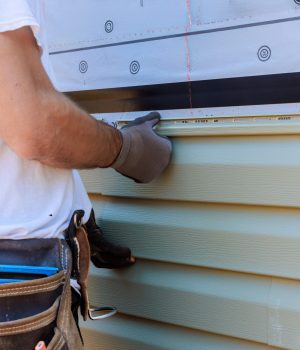 Handyman process installing vinyl PVC siding during construction on facade new home